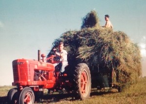 Uncle Rand driving the tractor while my dad, the older brother, pitches the hay.